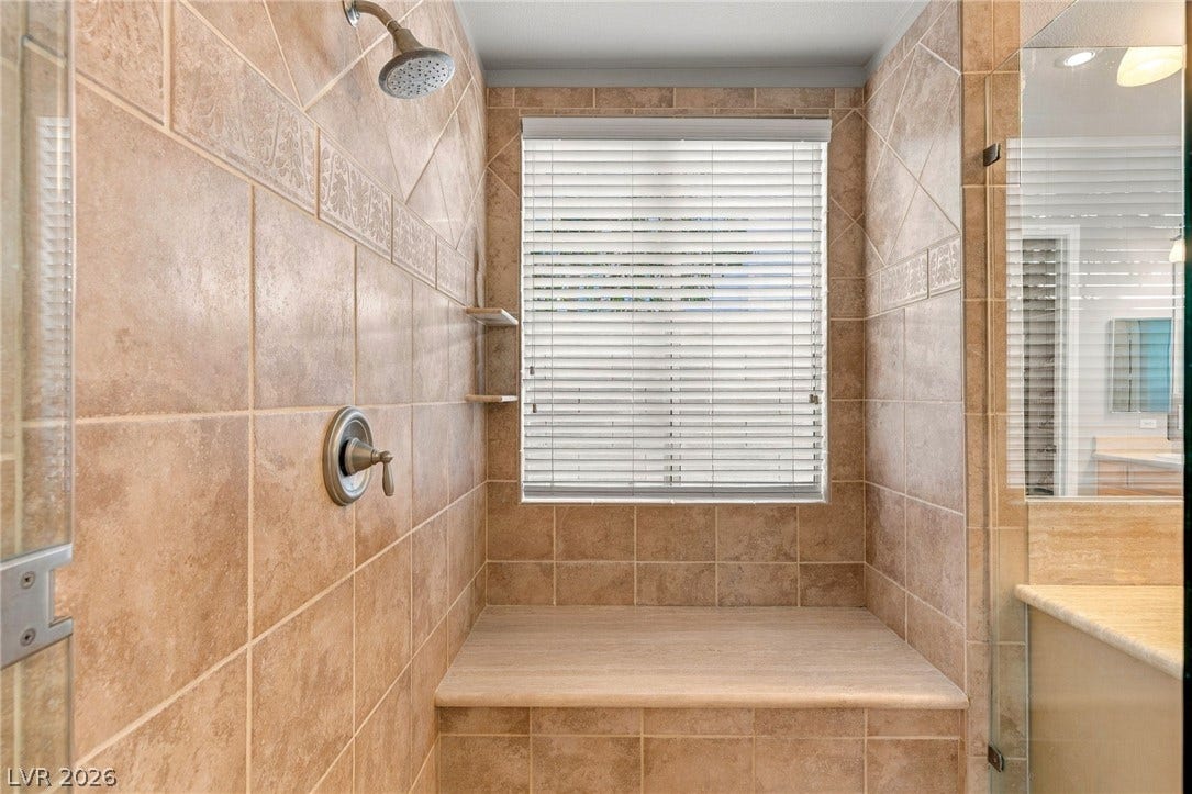 2984 Via Della Amore, Henderson, NV 89052 Floor-to-ceiling tiling and a built-in bench seat define this walk-in shower enclosure.