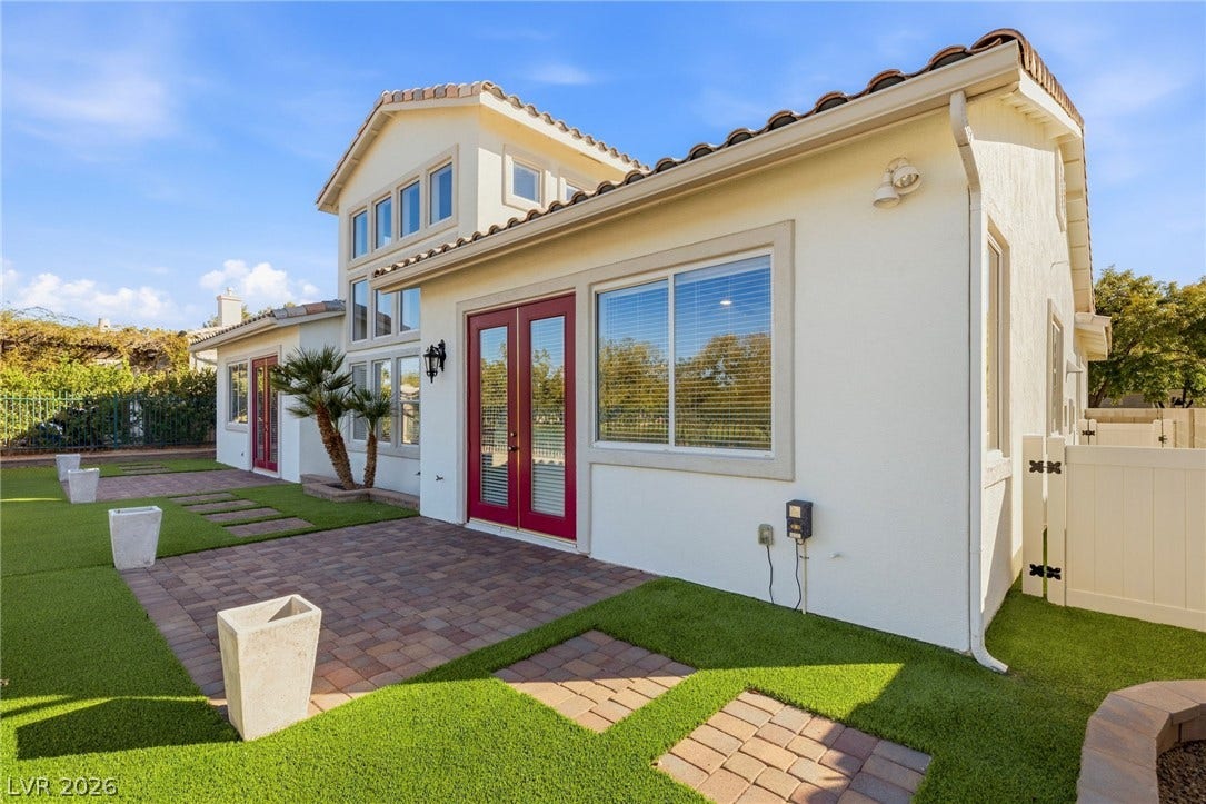 2984 Via Della Amore, Henderson, NV 89052 French doors open directly onto a paved backyard patio framed by green turf.