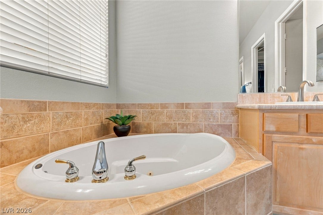 2984 Via Della Amore, Henderson, NV 89052 Tiled surrounds frame a built-in soaking tub beneath horizontal window blinds.
