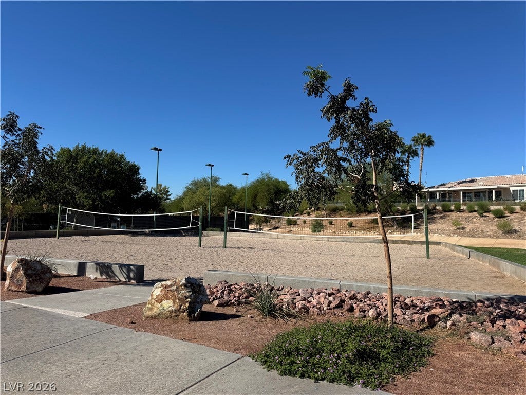 2984 Via Della Amore, Henderson, NV 89052 Two sand volleyball courts sit adjacent to concrete walkways under a clear blue sky.