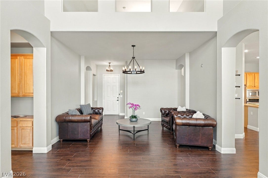 2984 Via Della Amore, Henderson, NV 89052 Arched doorways frame a spacious living area highlighted by rich wood floors and high ceilings.