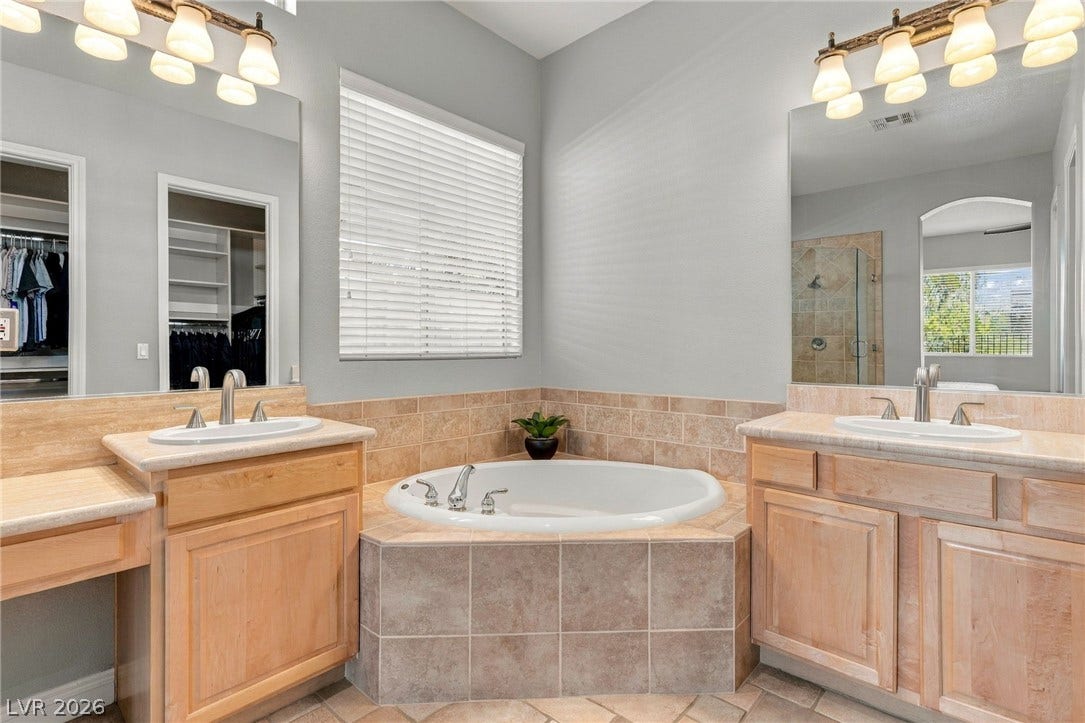 2984 Via Della Amore, Henderson, NV 89052 Natural light filters through the window, illuminating the corner tub and dual vanities.