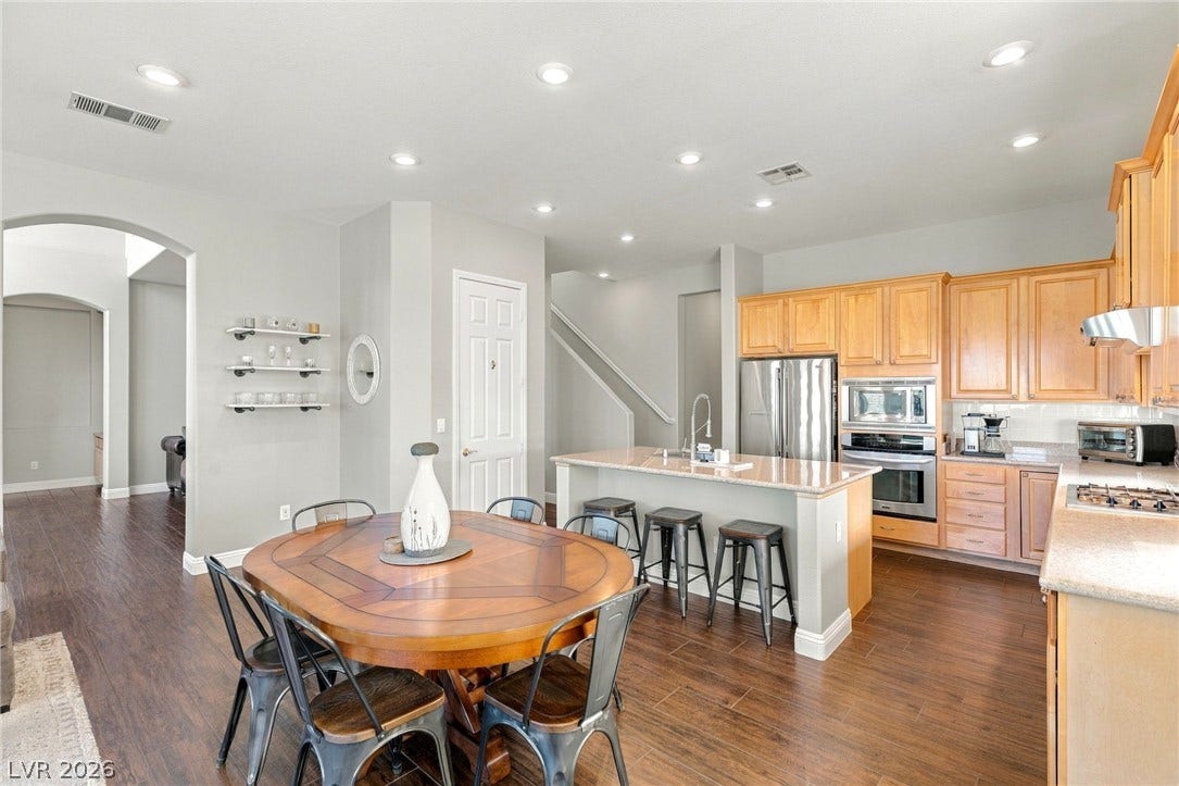 2984 Via Della Amore, Henderson, NV 89052 Rich wood flooring runs through this airy kitchen with stone countertops and classic cabinetry.