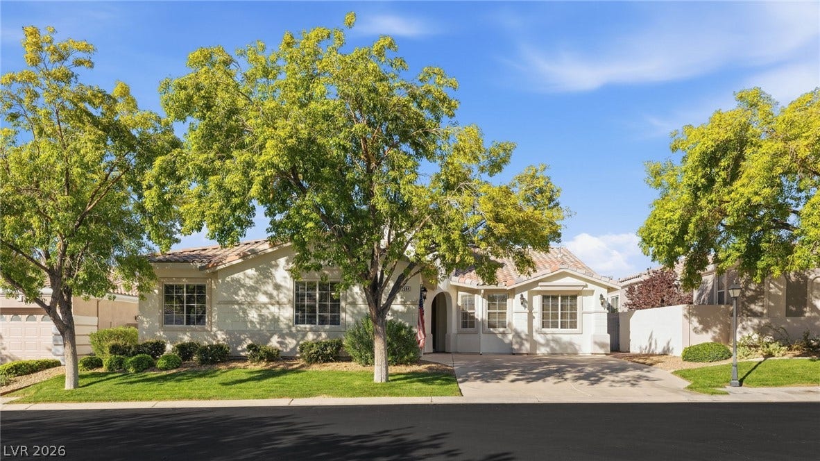 2984 Via Della Amore, Henderson, NV 89052 Mature trees frame the stucco exterior and tiled roof of this one-story suburban home.