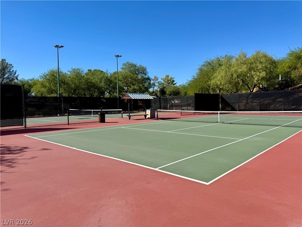 2984 Via Della Amore, Henderson, NV 89052 Professional-grade outdoor tennis courts sit surrounded by mature trees under clear blue skies.