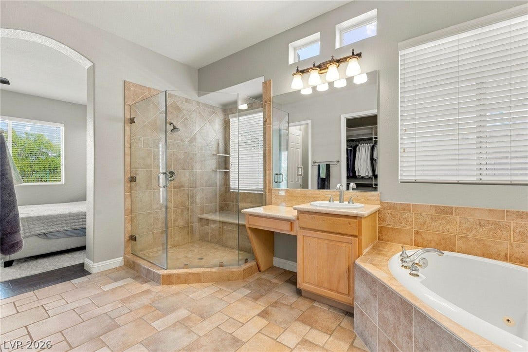 2984 Via Della Amore, Henderson, NV 89052 A glass-enclosed shower, built-in soaking tub, and tile floors complete this primary bathroom retreat.