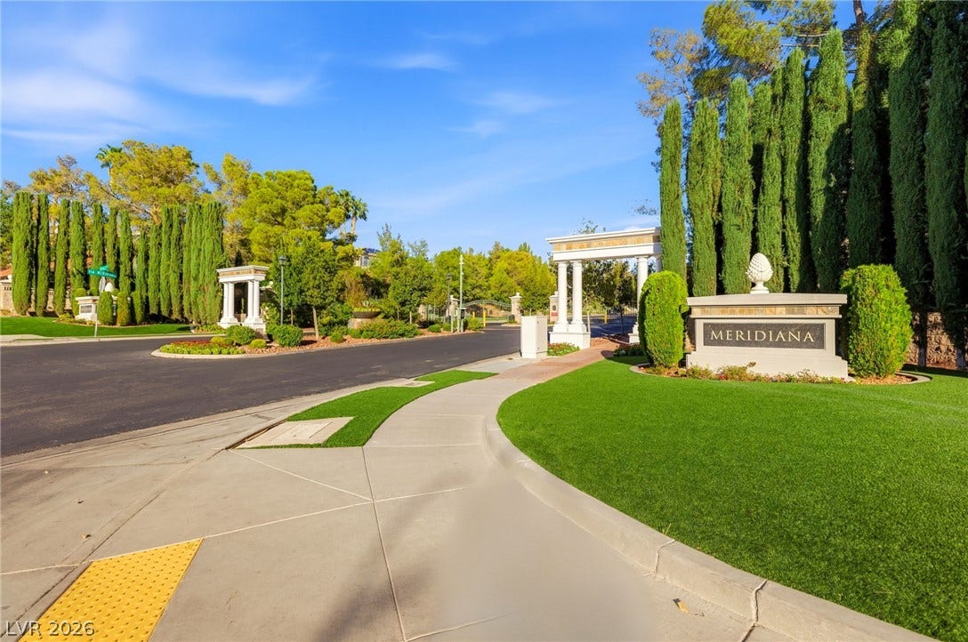 2984 Via Della Amore, Henderson, NV 89052 A grand gated entrance with manicured lawns and towering cypress trees leads into the neighborhood.
