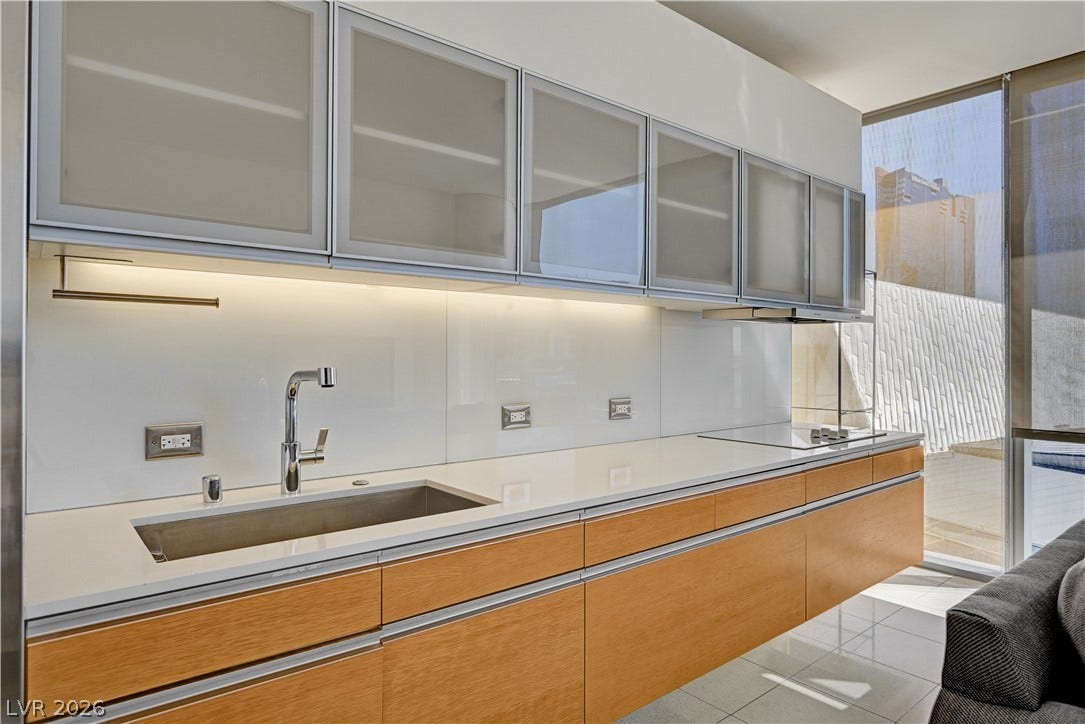 3722 Las Vegas Boulevard, #303, Las Vegas, NV 89158 Sleek under-cabinet lighting illuminates clean countertops and minimalist wood cabinetry next to floor-to-ceiling windows.