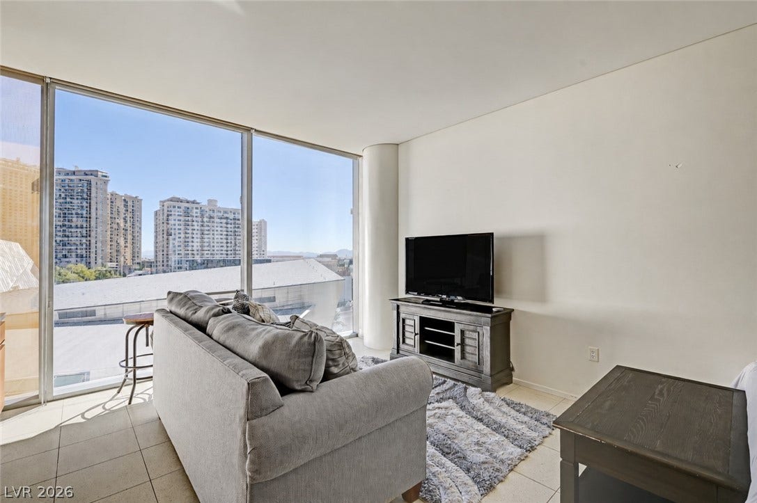 3722 Las Vegas Boulevard, #303, Las Vegas, NV 89158 Towering floor-to-ceiling windows frame cityscape views in this tiled living area.