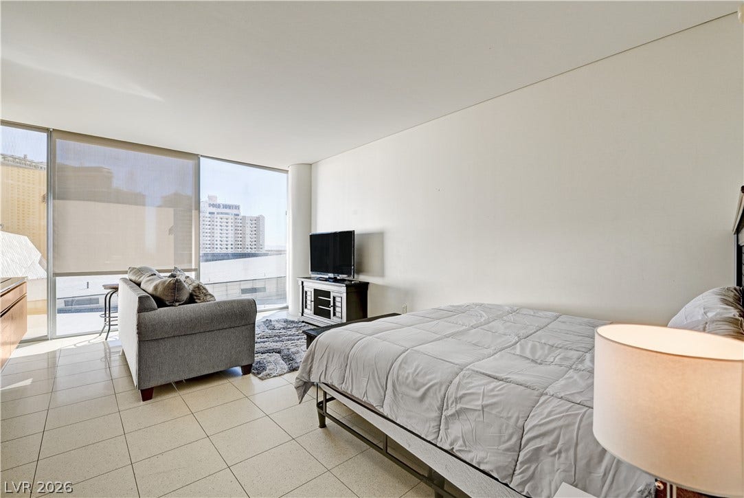 3722 Las Vegas Boulevard, #303, Las Vegas, NV 89158 Floor-to-ceiling windows frame dynamic city views in this modern bedroom with tiled flooring.