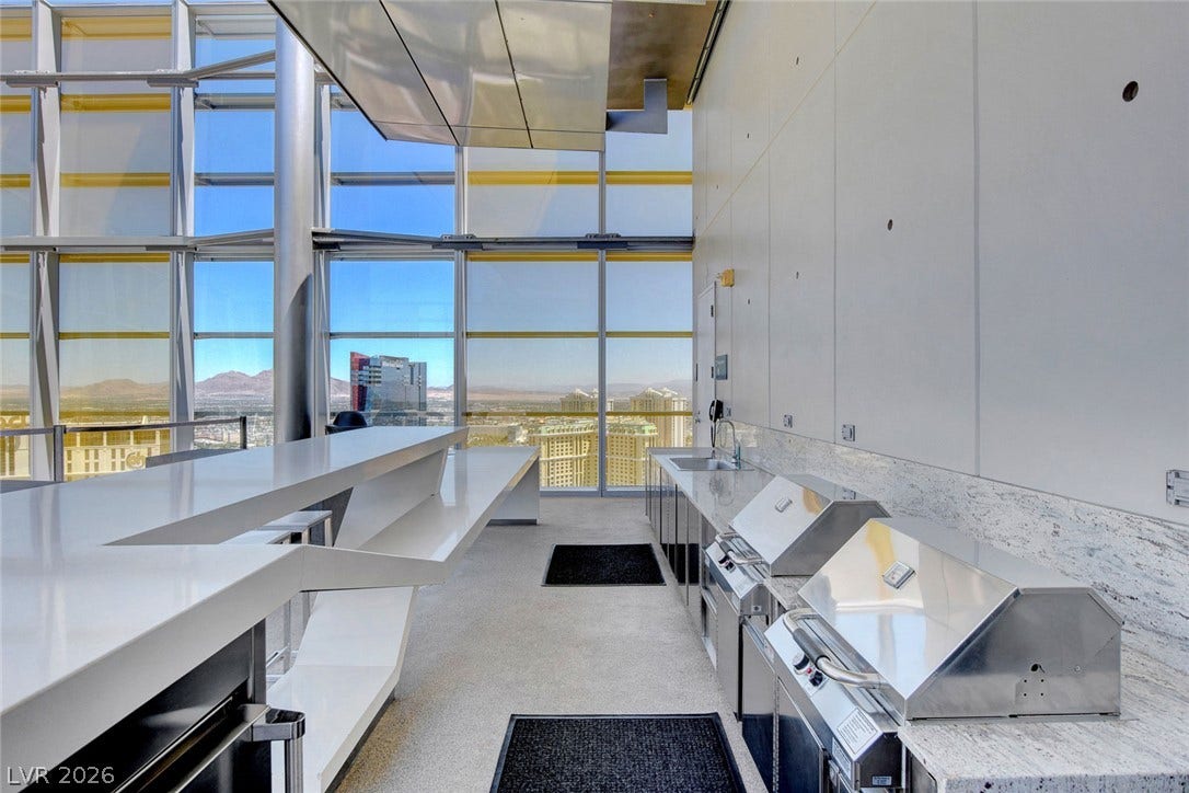 3722 Las Vegas Boulevard, #303, Las Vegas, NV 89158 Towering floor-to-ceiling windows frame expansive city and mountain views from this modern indoor kitchen space.