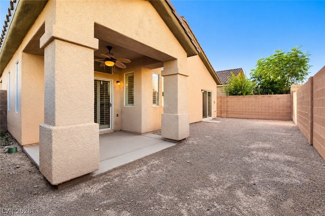 6729 Quarterhorse Lane, Las Vegas, NV 89148 Private backyard featuring a covered patio with ceiling fan, block-wall fencing, low-maintenance landscaping, and an open yard ready to personalize with outdoor living, entertaining, or garden space.