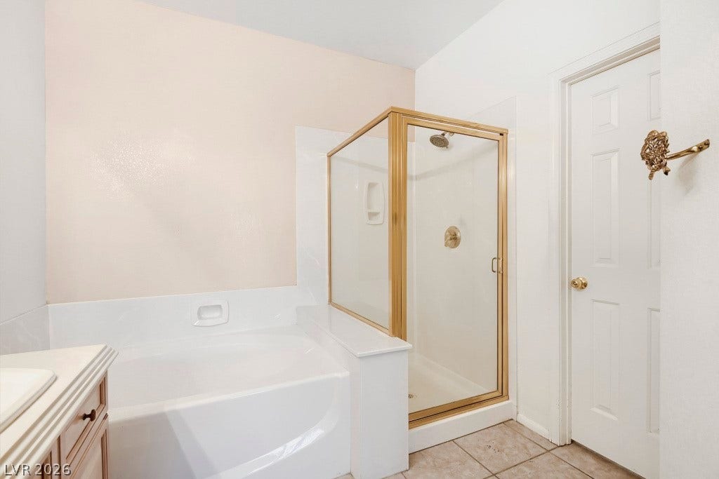 6729 Quarterhorse Lane, Las Vegas, NV 89148 Primary bathroom featuring a separate soaking tub and glass-enclosed walk-in shower, neutral tile flooring, and direct access to the primary walk-in closet.