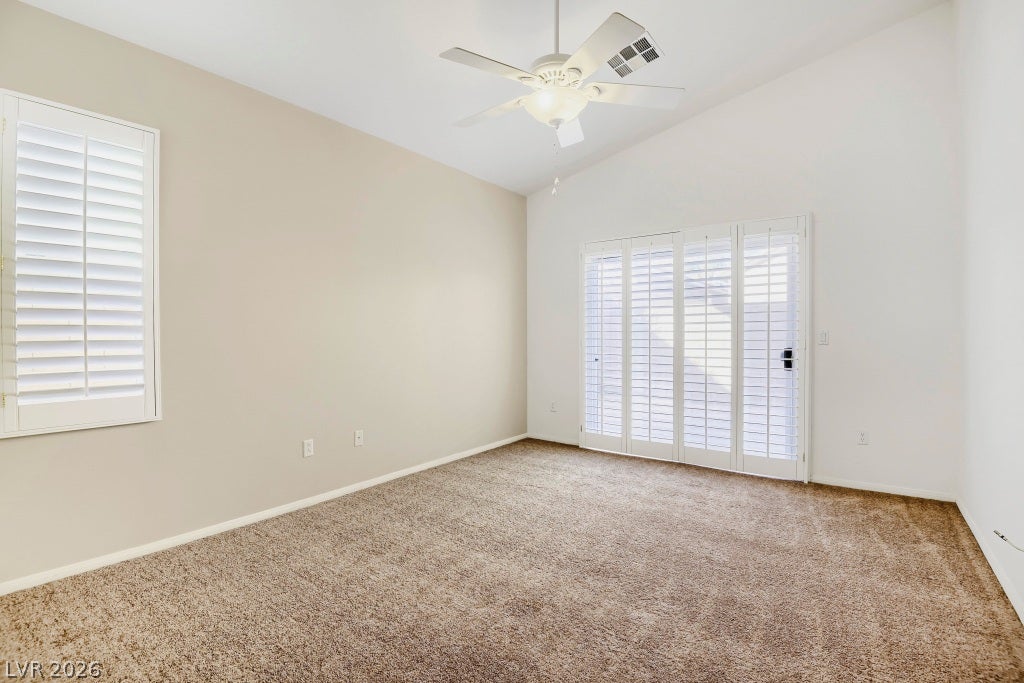 6729 Quarterhorse Lane, Las Vegas, NV 89148 Spacious primary bedroom featuring vaulted ceilings, new plush carpet, ceiling fan with light, plantation shutters, abundant natural light, and sliding door with plantation shutters providing direct access to the backyard.