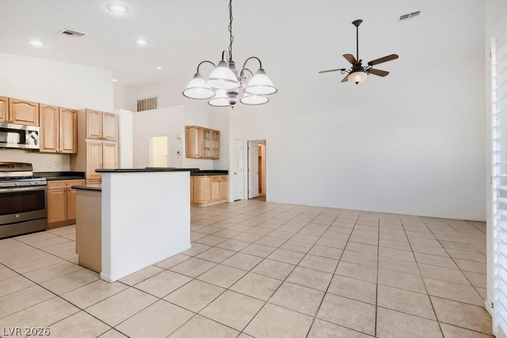 6729 Quarterhorse Lane, Las Vegas, NV 89148 Open-concept dining and living area showcasing vaulted ceilings, neutral tile flooring, recessed lighting, decorative dining chandelier, ceiling fan, and seamless flow into the kitchen and great room.