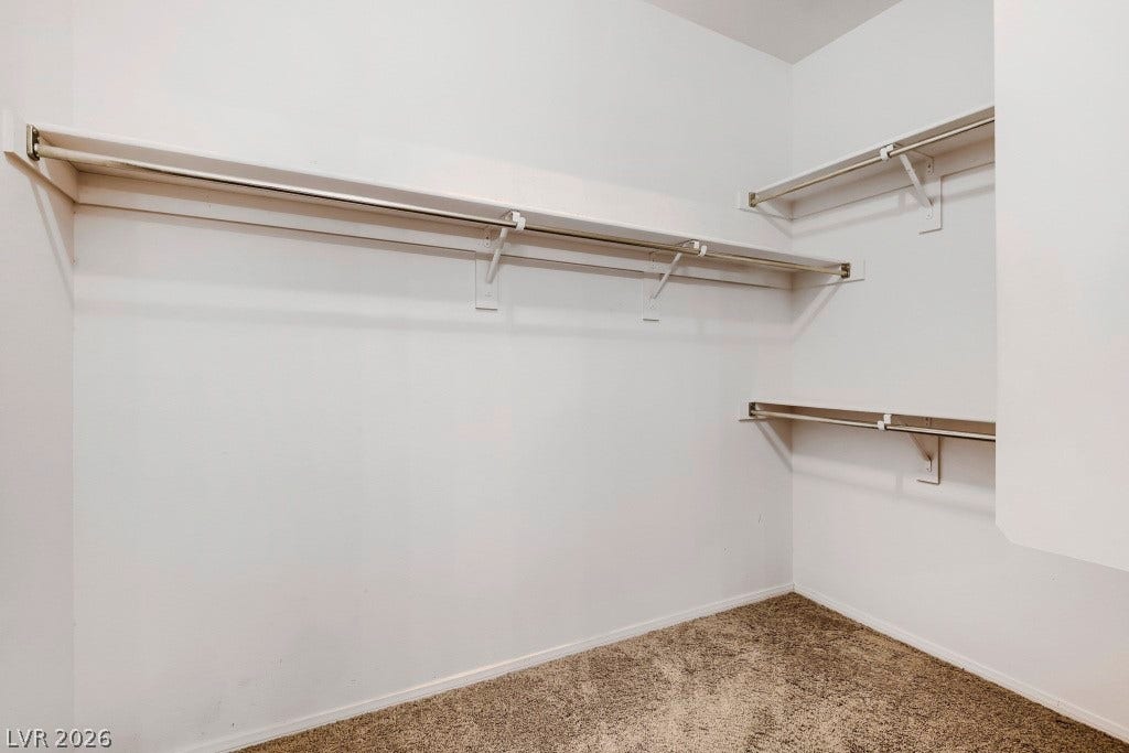 6729 Quarterhorse Lane, Las Vegas, NV 89148 Generously sized (6"x9") primary walk-in closet featuring multiple hanging rods, upper shelving, carpet flooring, and ample space for wardrobe and additional storage.