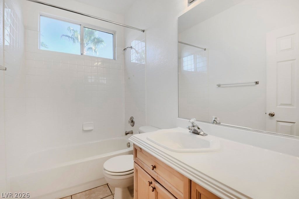 6729 Quarterhorse Lane, Las Vegas, NV 89148 Full secondary bathroom featuring a spacious vanity with wood cabinetry, tub/shower combination with tile surround, large wall mirror, neutral tile flooring, and a window providing natural light.