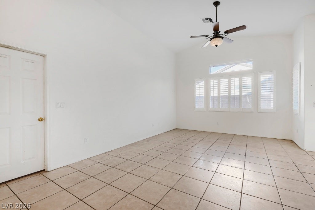 6729 Quarterhorse Lane, Las Vegas, NV 89148 Spacious great room filled with natural light featuring vaulted ceilings, neutral tile flooring, ceiling fan with light fixture, plantation shutters, multiple windows, and an open layout flowing into the dining area and kitchen.