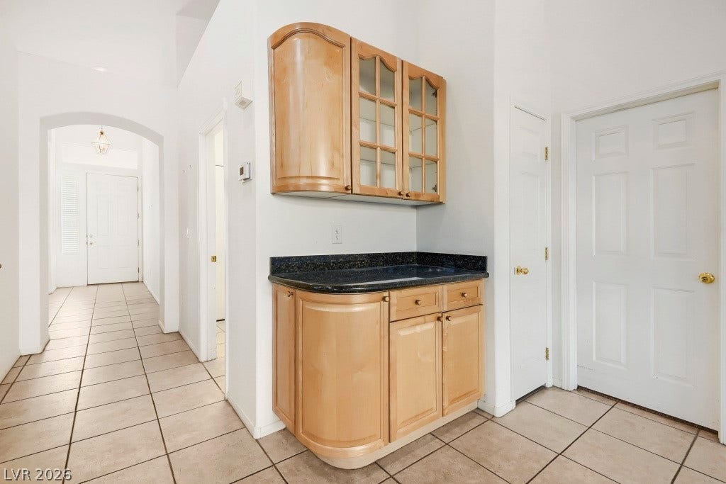 6729 Quarterhorse Lane, Las Vegas, NV 89148 Bright entry and hallway feature neutral tile flooring and built-in wood cabinetry with glass-front upper cabinets, granite countertop, lower storage cabinets, and convenient additional storage just off the main living area.