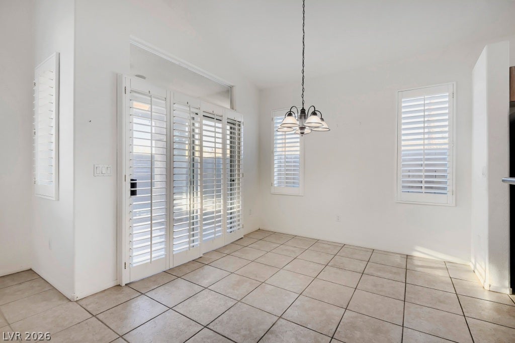 6729 Quarterhorse Lane, Las Vegas, NV 89148 Spacious great room filled with natural light featuring vaulted ceilings, neutral tile flooring, ceiling fan with light fixture, plantation shutters, multiple windows, and an open layout flowing into the dining area and kitchen.