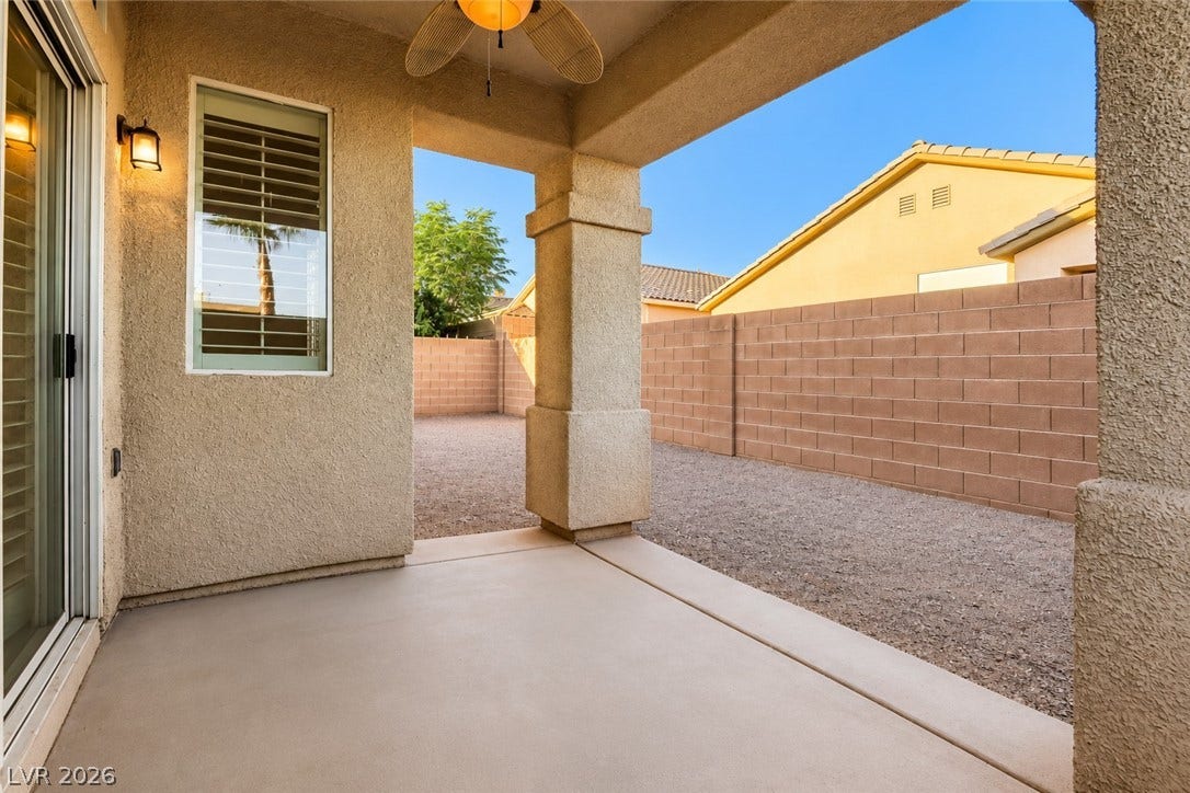 6729 Quarterhorse Lane, Las Vegas, NV 89148 Covered backyard patio featuring a ceiling fan with light, exterior lighting, stucco columns, and convenient access from the interior, creating a shaded outdoor space for relaxing or entertaining.