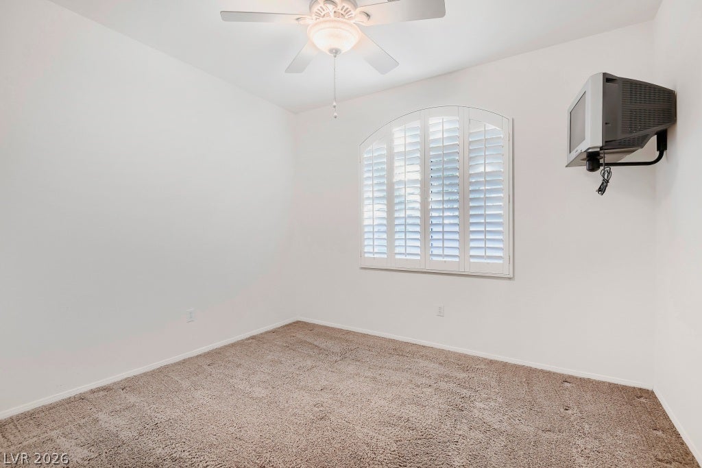 6729 Quarterhorse Lane, Las Vegas, NV 89148 Bright secondary bedroom (12"x13") featuring neutral carpet, ceiling fan with light, plantation shutters, arched window detail, and abundant natural light.