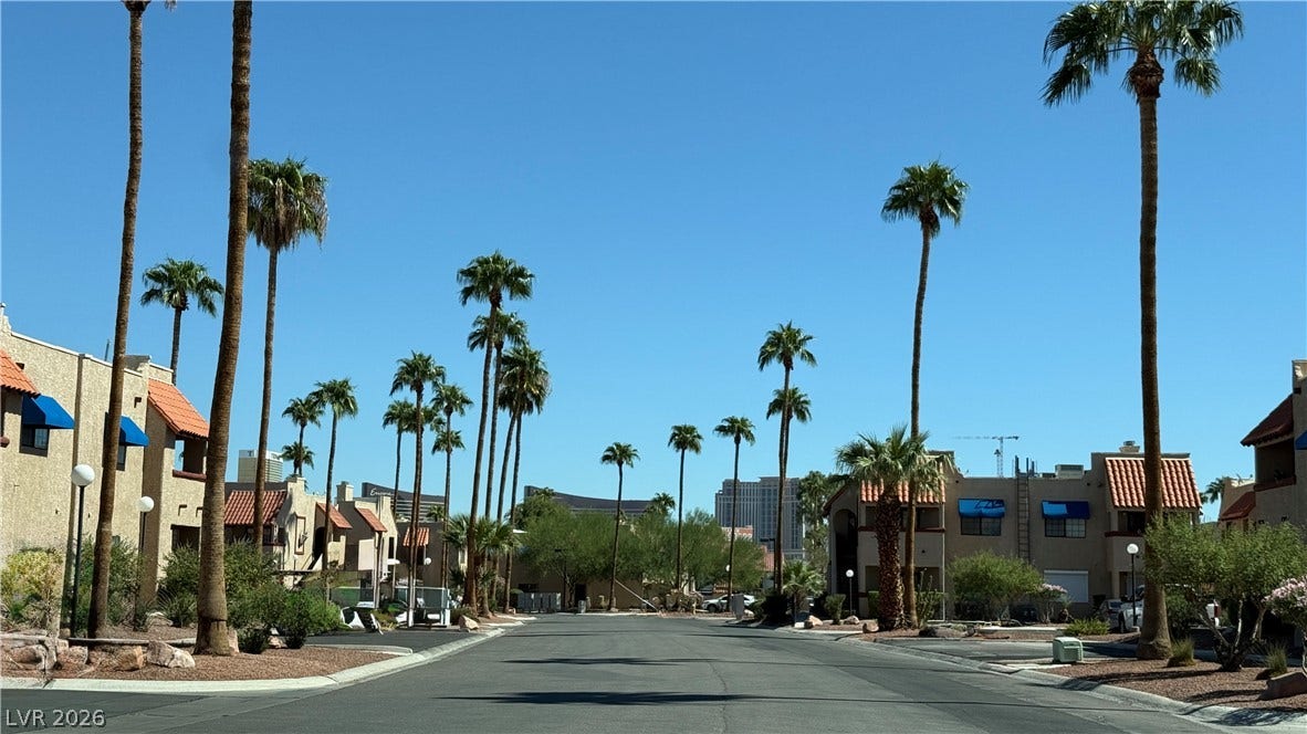 4321 Gannet Circle, #199, Las Vegas, NV 89103 Strip view and towering palm trees line a quiet neighborhood street under clear blue skies.