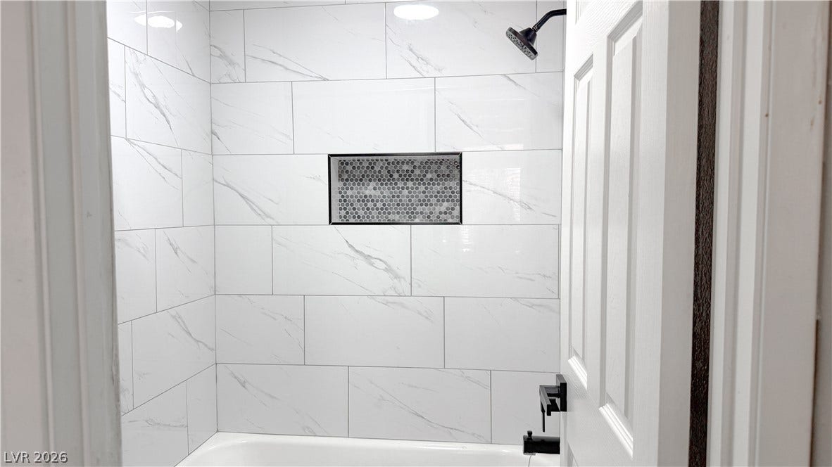 4321 Gannet Circle, #199, Las Vegas, NV 89103 Gleaming marble-patterned wall tiles and a built-in recessed niche elevate this modern shower surround.