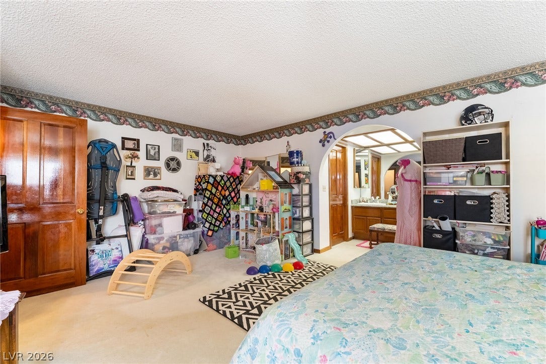 An arched doorway connects the carpeted bedroom space to the adjacent vanity area.