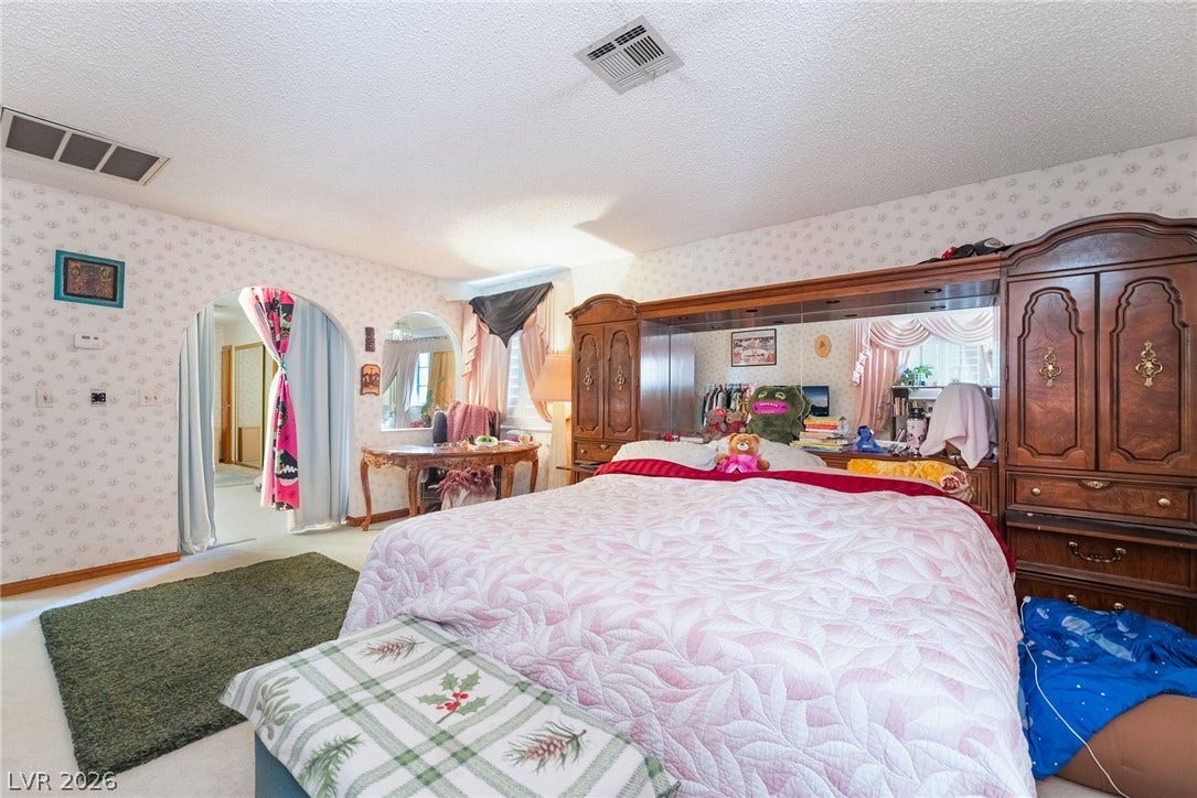 Arched doorways and classic patterned walls define this comfortable, carpeted private retreat.