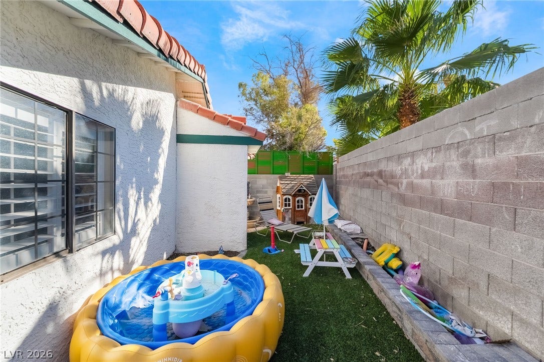 Secure block fencing borders a private side yard space set beneath clear desert skies.