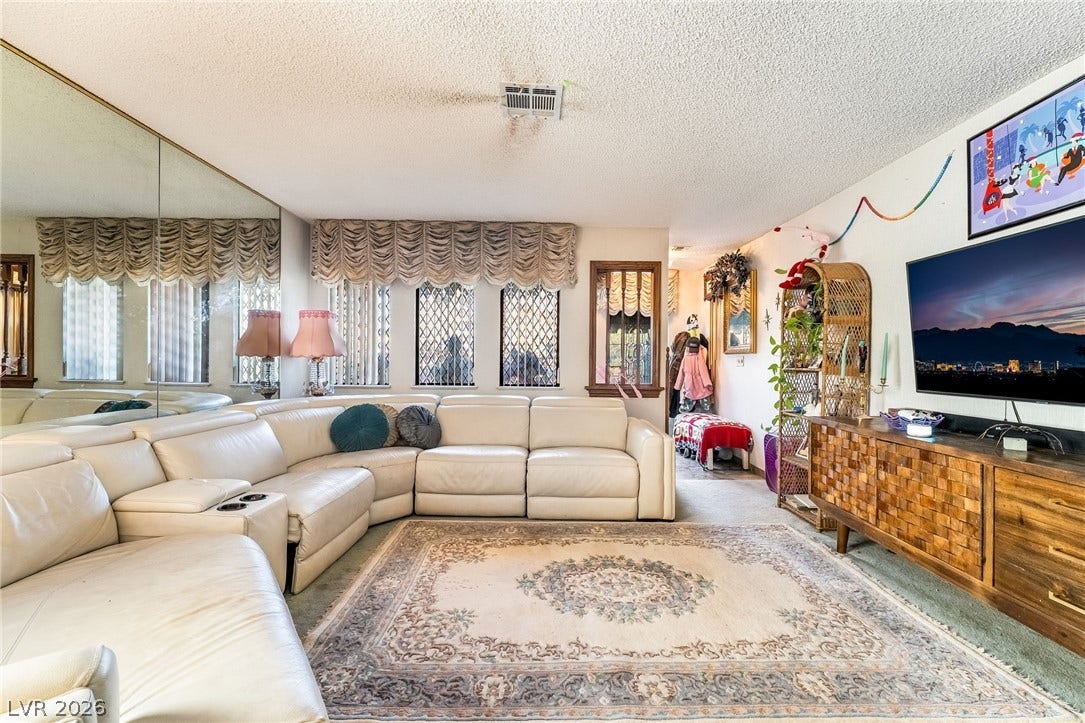 A spacious living area featuring mirrored wall panels and windows that fill the space with light.