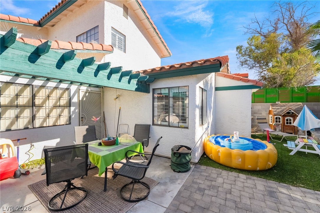 A classic Spanish tile roof and matching pergola accent this versatile concrete and paver patio.