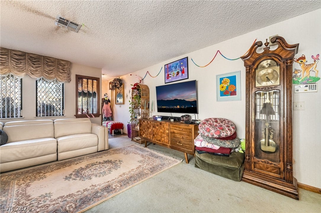 A spacious living area features soft carpet flooring underfoot and textured ceilings.