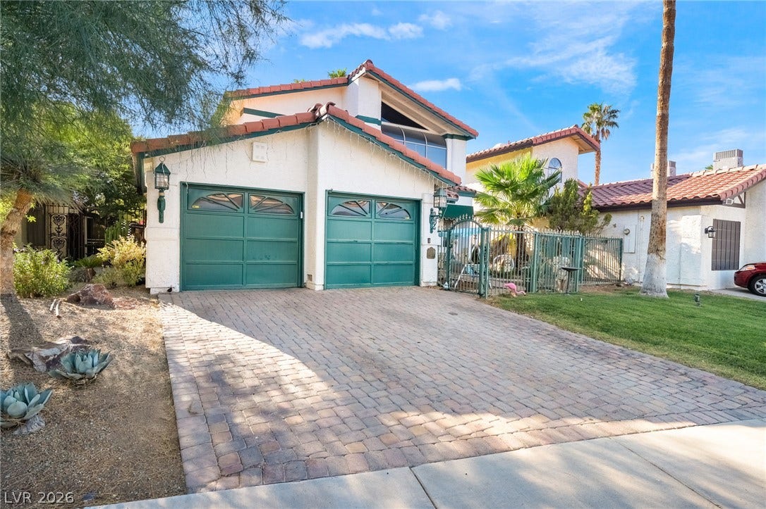 A spacious paved driveway leads to the two-car garage of this multi-level stucco home.