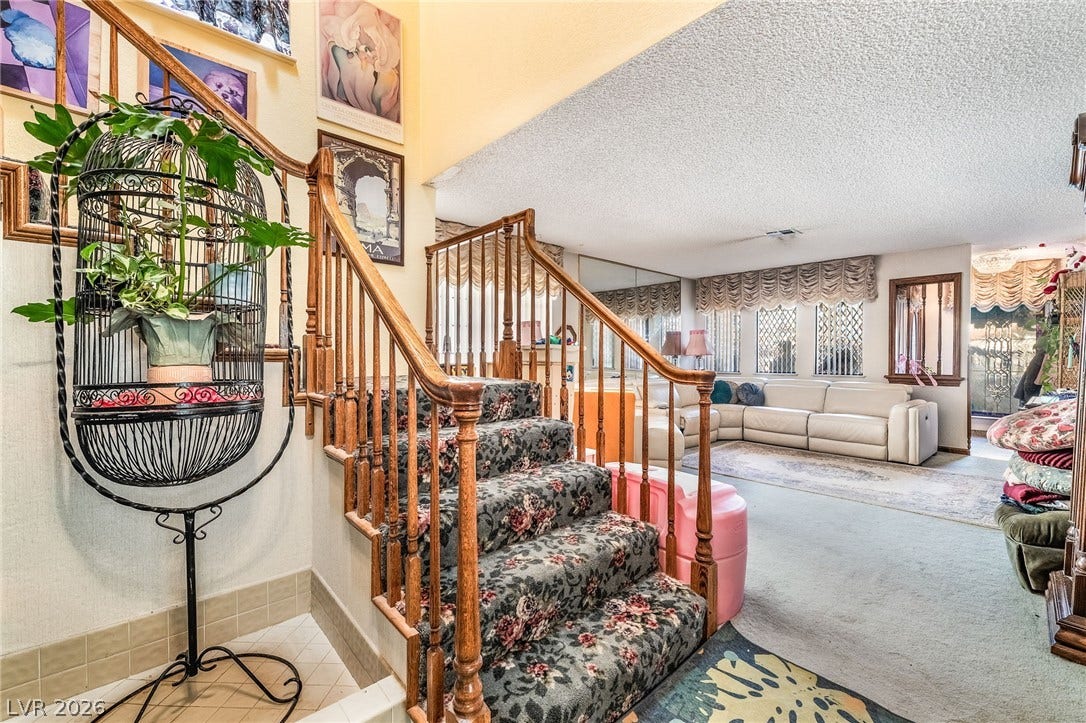 A spacious entryway features a classic wooden staircase leading to the upper level.