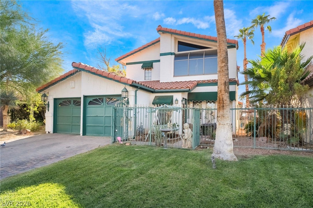 Spanish tile roofing and custom green trim elevate this multi-level home's stucco exterior.