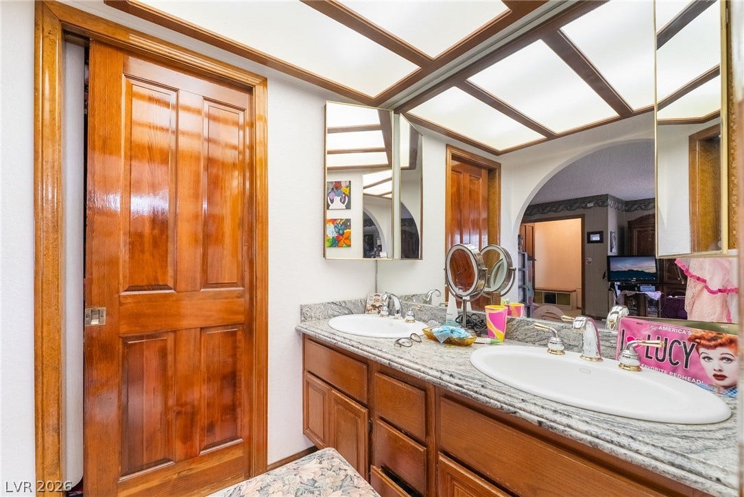 Rich wood cabinetry paired with stone countertops defines this well-appointed bathroom space.