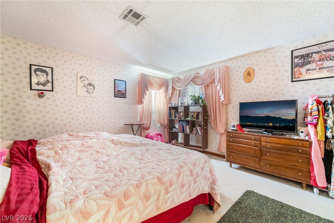 Patterned wallpaper and soft natural light define this cozy bedroom space.