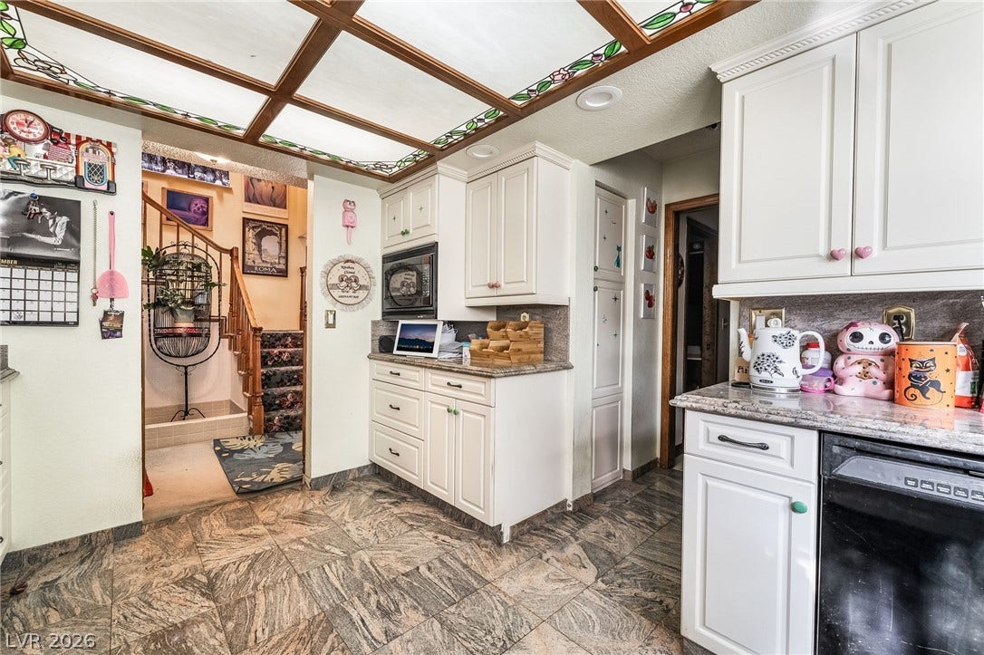 Granite counters and custom cabinetry complement stone tile flooring in this classic kitchen.