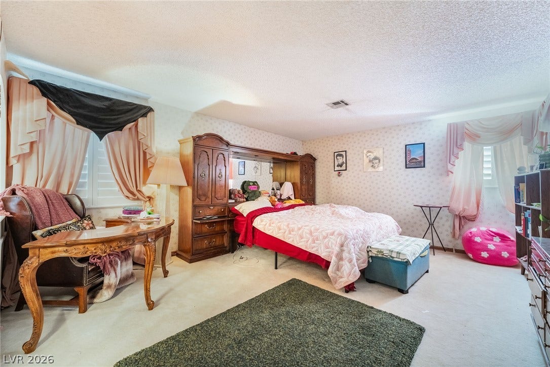 A spacious bedroom features wall-to-wall carpeting and multiple large windows.
