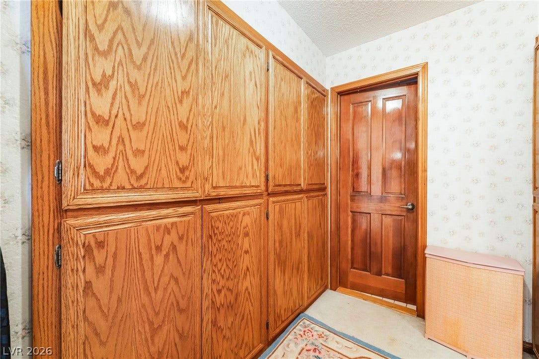 Abundant built-in storage cabinets line the hallway adjacent to a handsome wood paneled door.