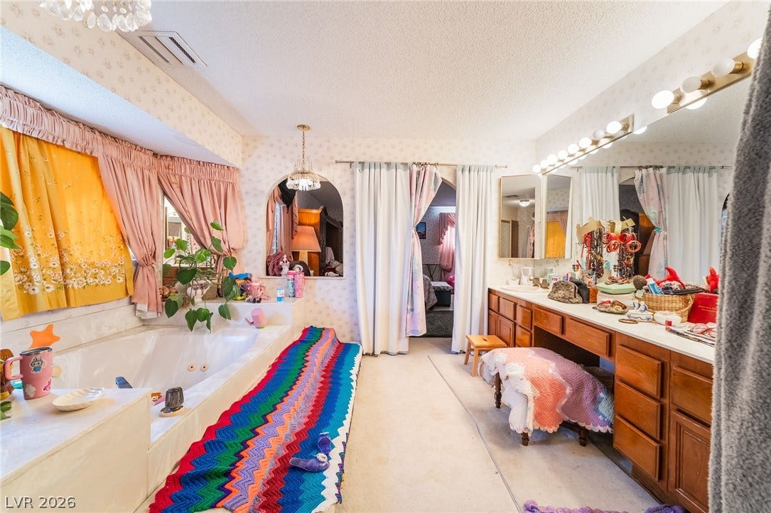 An expansive bathroom vanity area with a built-in makeup station sits opposite a soaking tub.