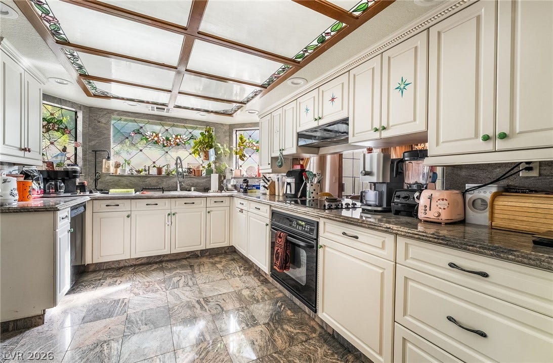 Gleaming stone tile floors support classic white cabinetry under a unique stained glass ceiling panel.