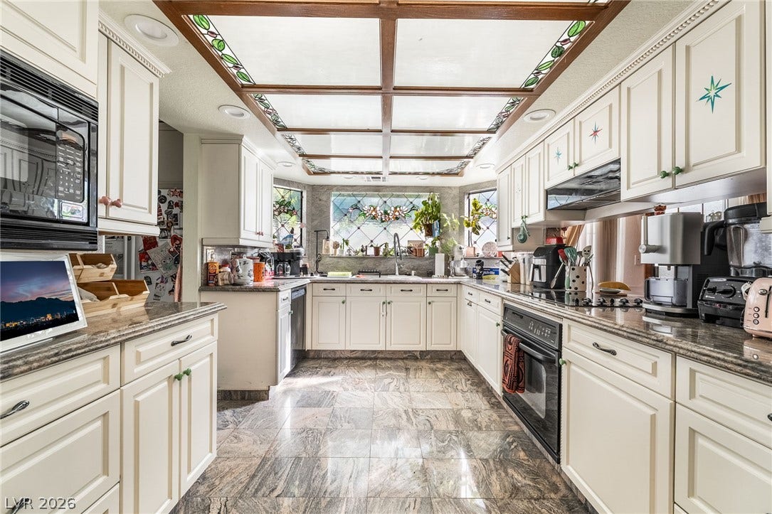 Polished stone flooring and a unique stained-glass ceiling panel highlight this spacious kitchen.