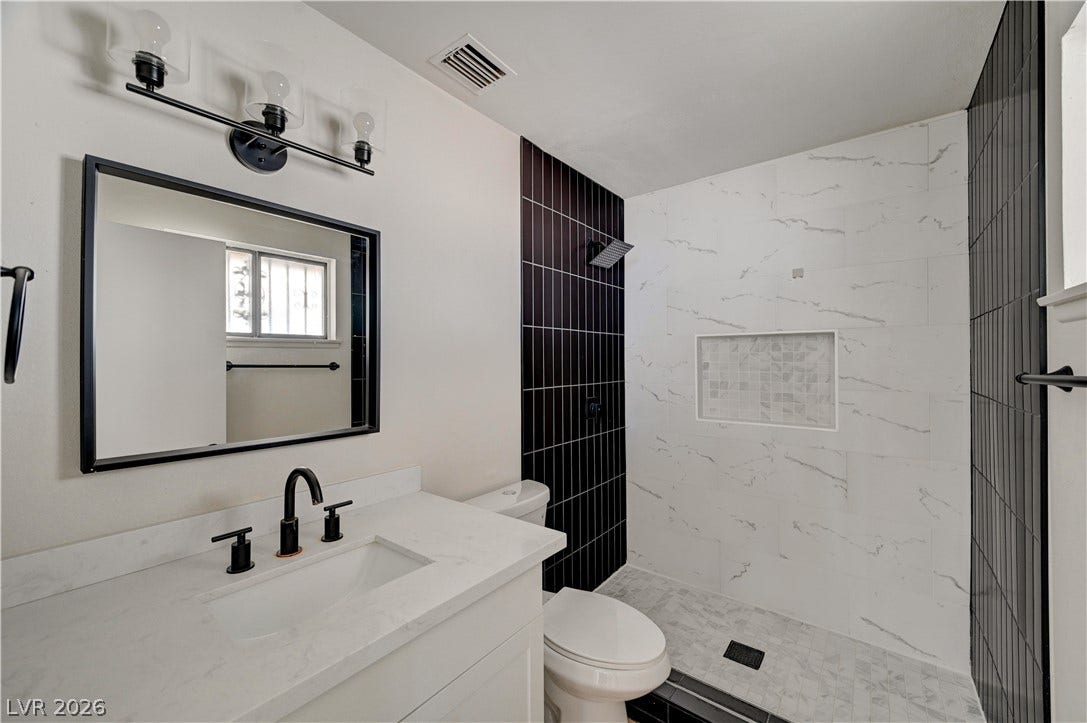 4442 Eureka Circle, Las Vegas, NV 89103 Contrast-rich modern tiling highlights the walk-in shower area of this renovated bathroom.