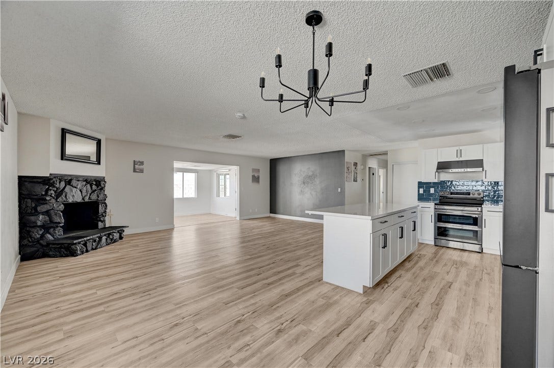4442 Eureka Circle, Las Vegas, NV 89103 A spacious open floorplan seamlessly connects the stone fireplace, kitchen island, and hardwood flooring.