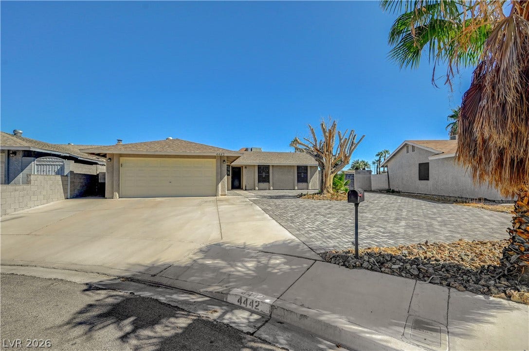 4442 Eureka Circle, Las Vegas, NV 89103 An expansive paved driveway leads to a classic stucco exterior with an attached garage.