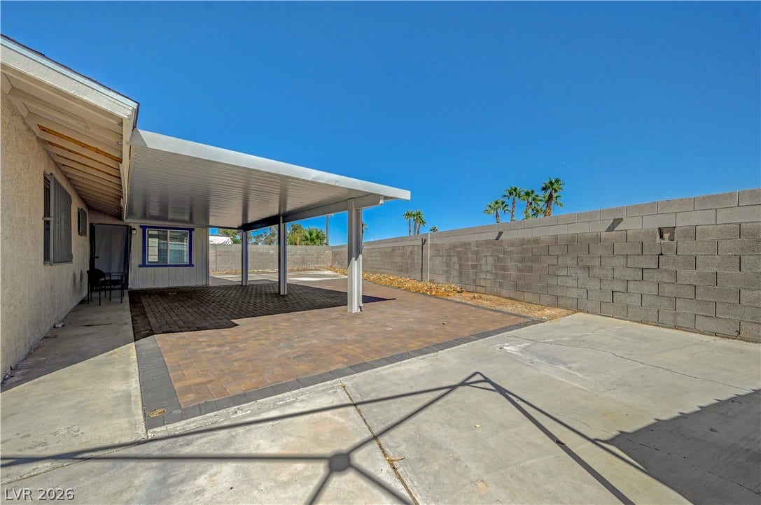 4442 Eureka Circle, Las Vegas, NV 89103 A spacious backyard patio features a protective covered awning and concrete block fencing.