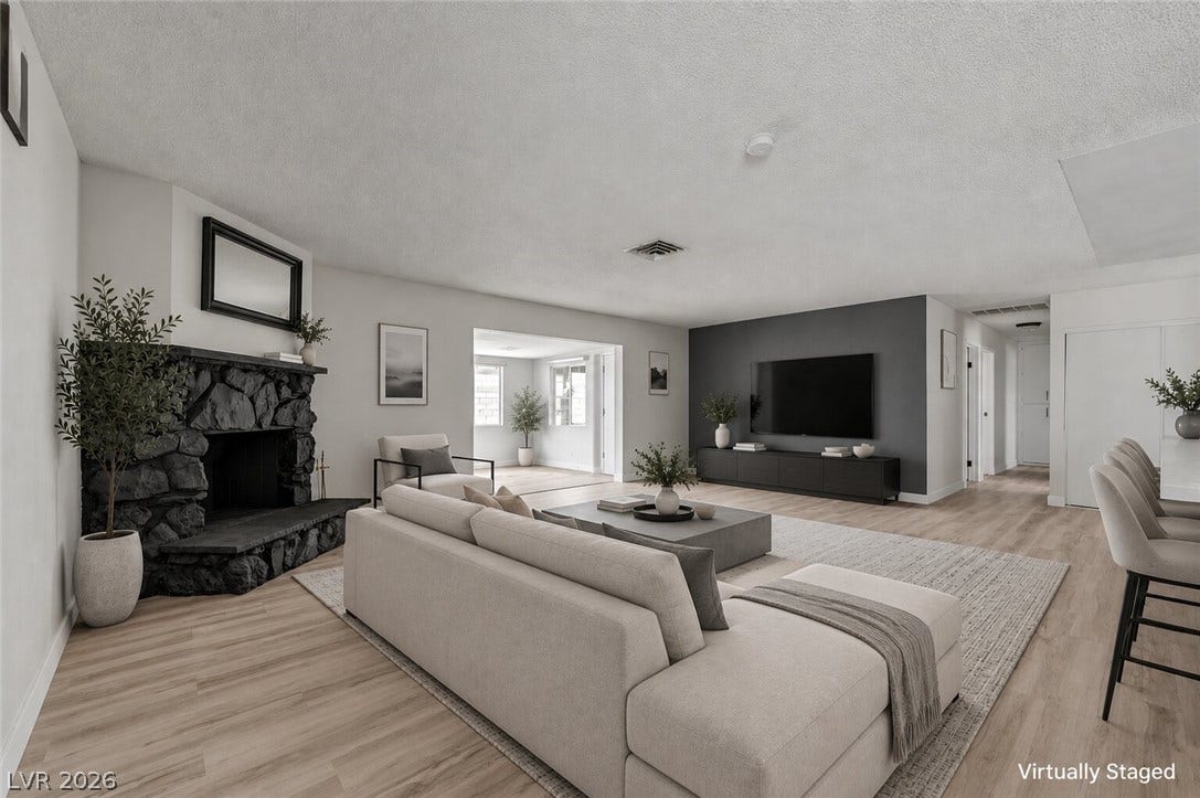 4442 Eureka Circle, Las Vegas, NV 89103 An inviting stone fireplace anchors this open living space featuring modern wood floors.